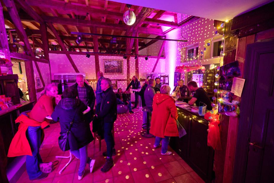 © Oliver Borchert Menschen stehen im bunten Licht an der Bar und unterhalten sich