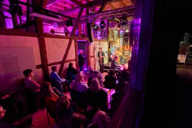 © Oliver Borchert Ein Blick durchs Fenster in die Museumsanlage, bei Nacht, mit einem beleuchteten Konzert